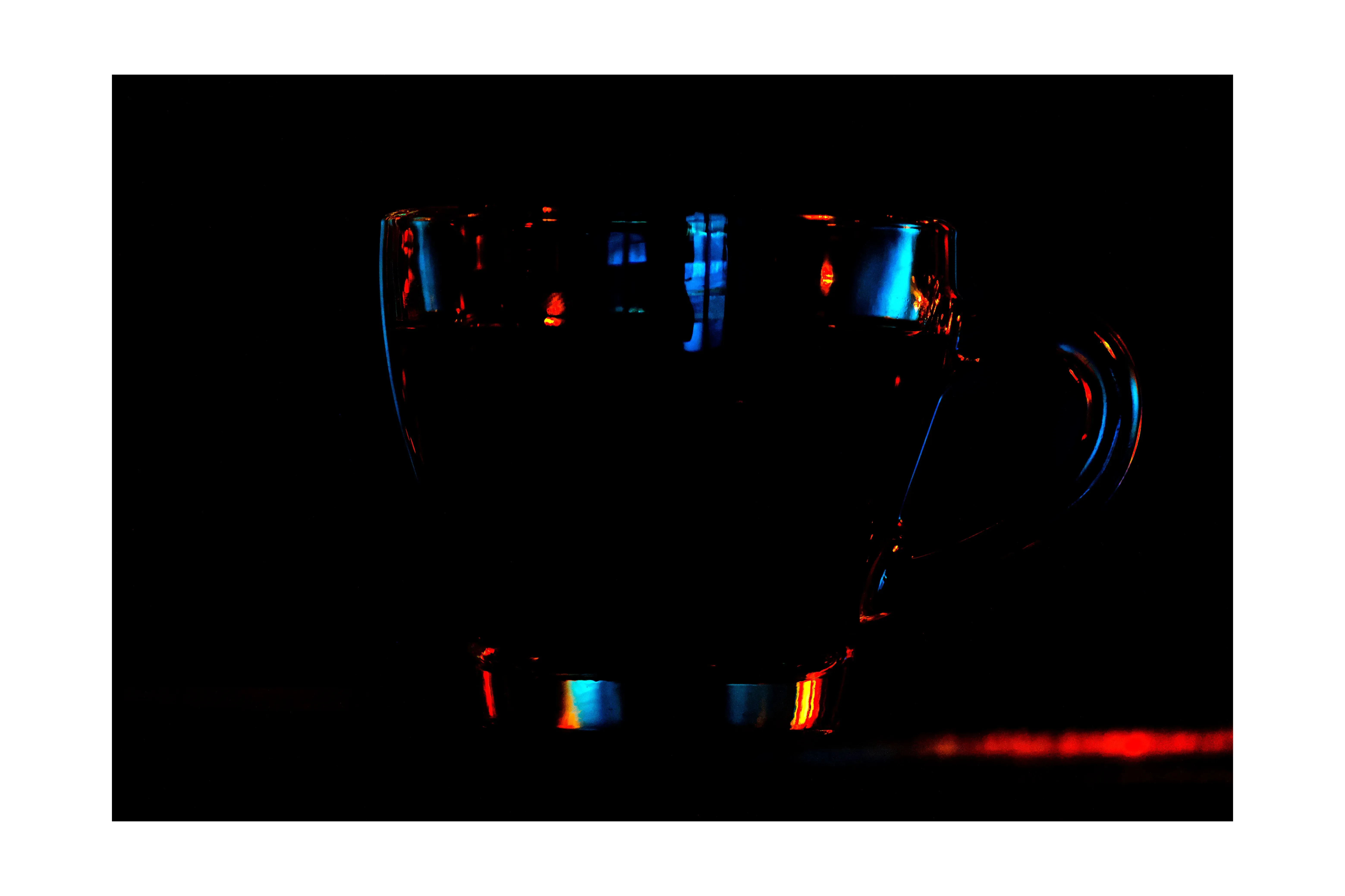 Tasse transparente avec reflets bleus et rouges sur fond noir